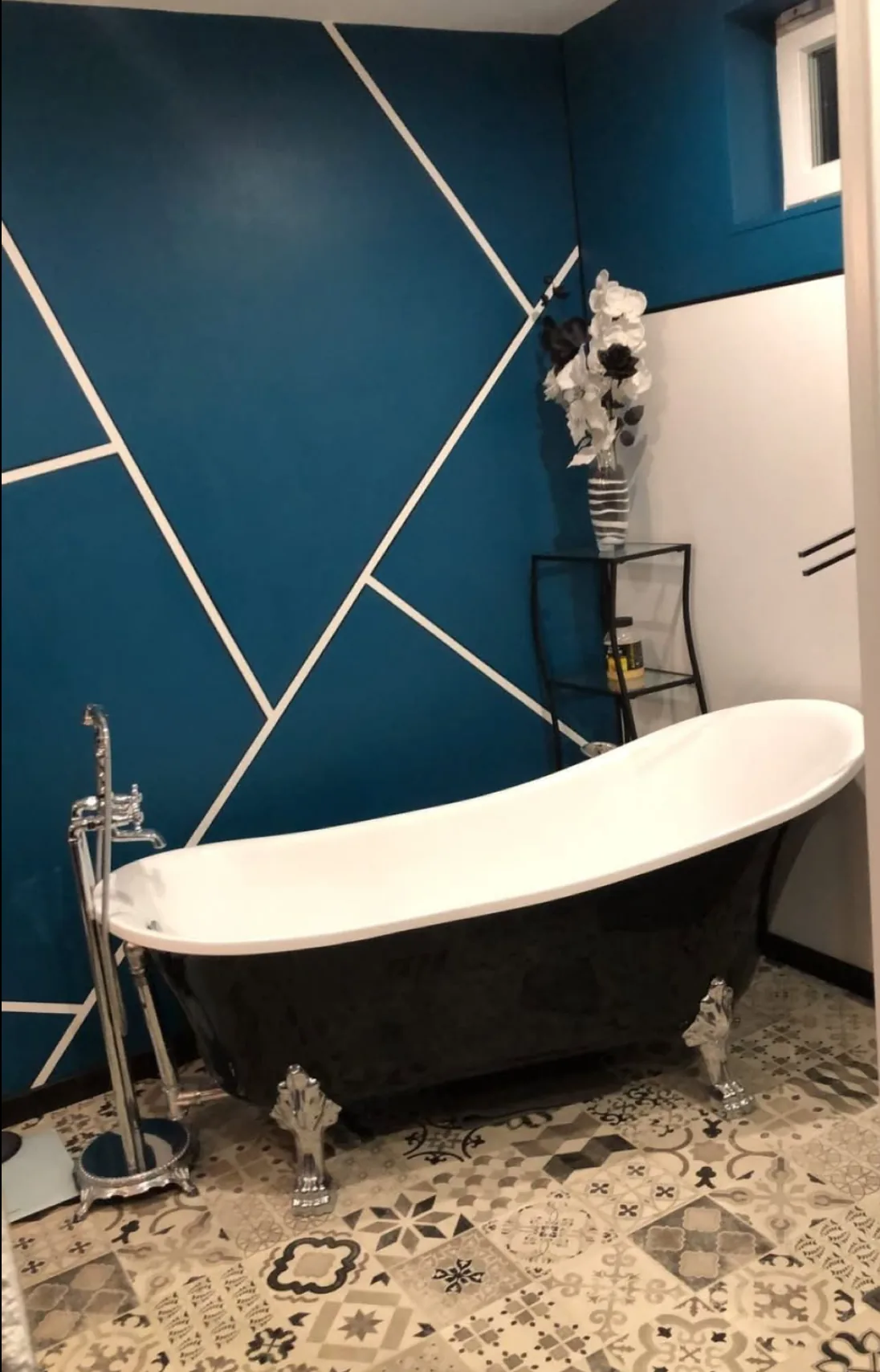 Mur bleu pétrole avec motif géométrique blanc dans une salle de bain
